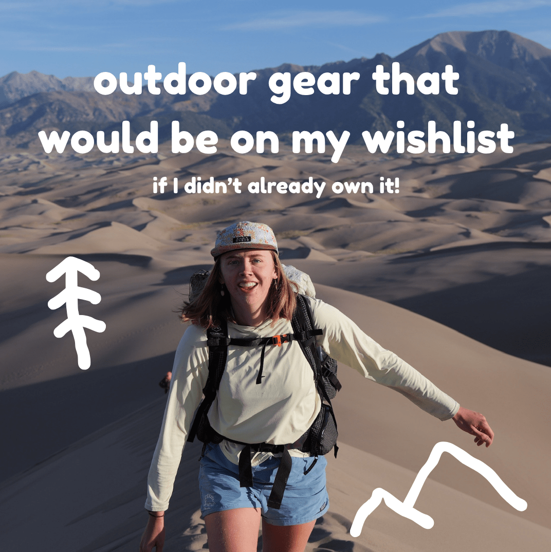 woman wearing backpacking smiling at camera with sand dunes in the background.